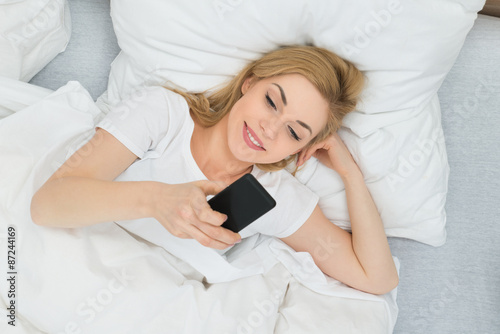 Woman With Mobile Phone In Bed