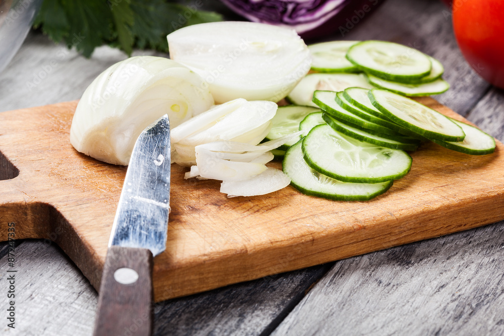 Chopped vegetables: onion and cucumber on cutting board Chopped vegetables: onion and cucumber on cutting board