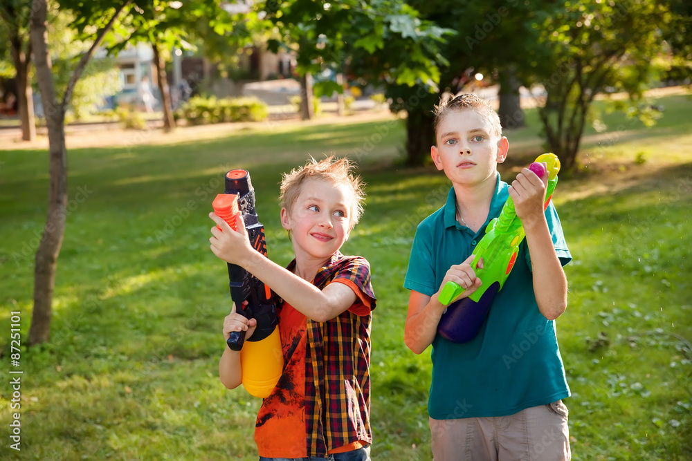 Fototapeta premium happy boys playing with water guns