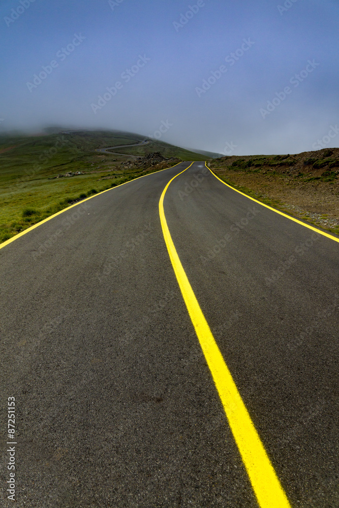 High altitude road into the mountains in foggy day