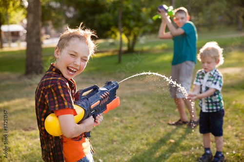 happy little boys playing with water guns