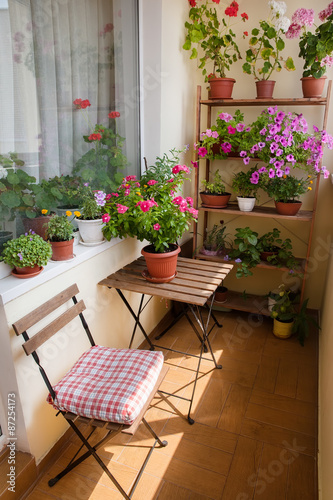 Beautiful balcony with small table, chair and flowers.