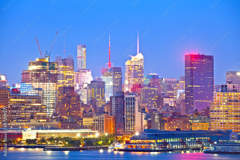 Obraz premium New York City skyline, modern illuminated colorful buildings in downtown Manhattan at sunset