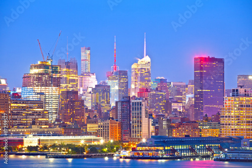 New York City skyline, modern illuminated colorful buildings in downtown Manhattan at sunset
