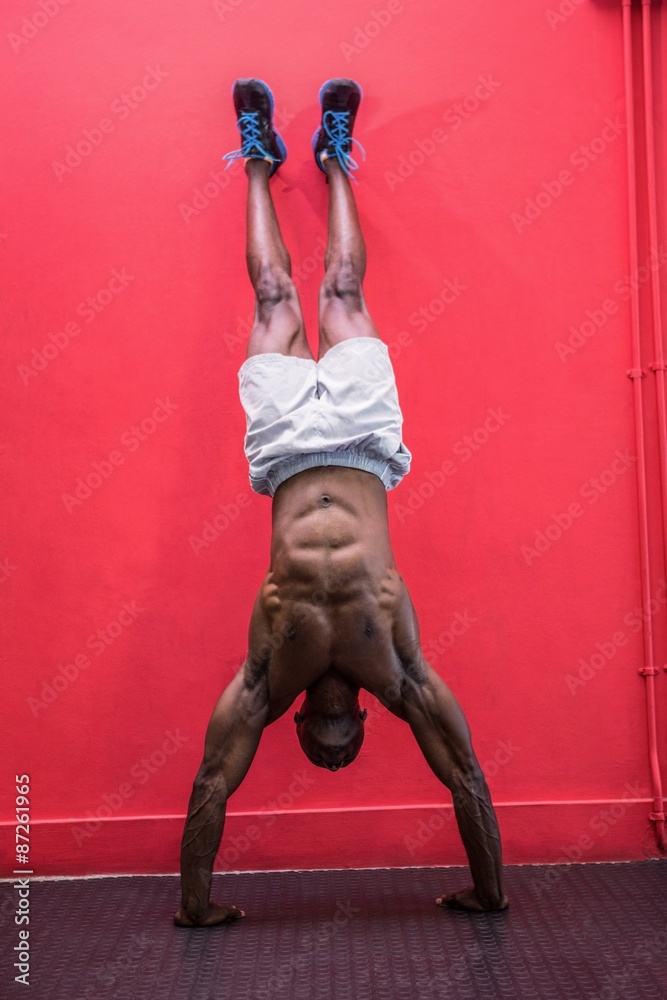 Young bodybuilder doing a handstand