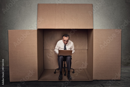 Obraz na plátne man working on laptop sitting on chair inside carton box
