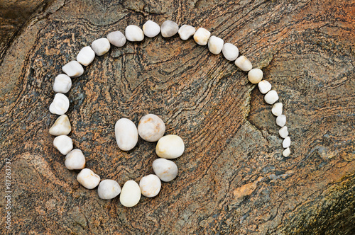 Esoterische Spirale aus weißen Kieselsteinen auf geädertem Felsen