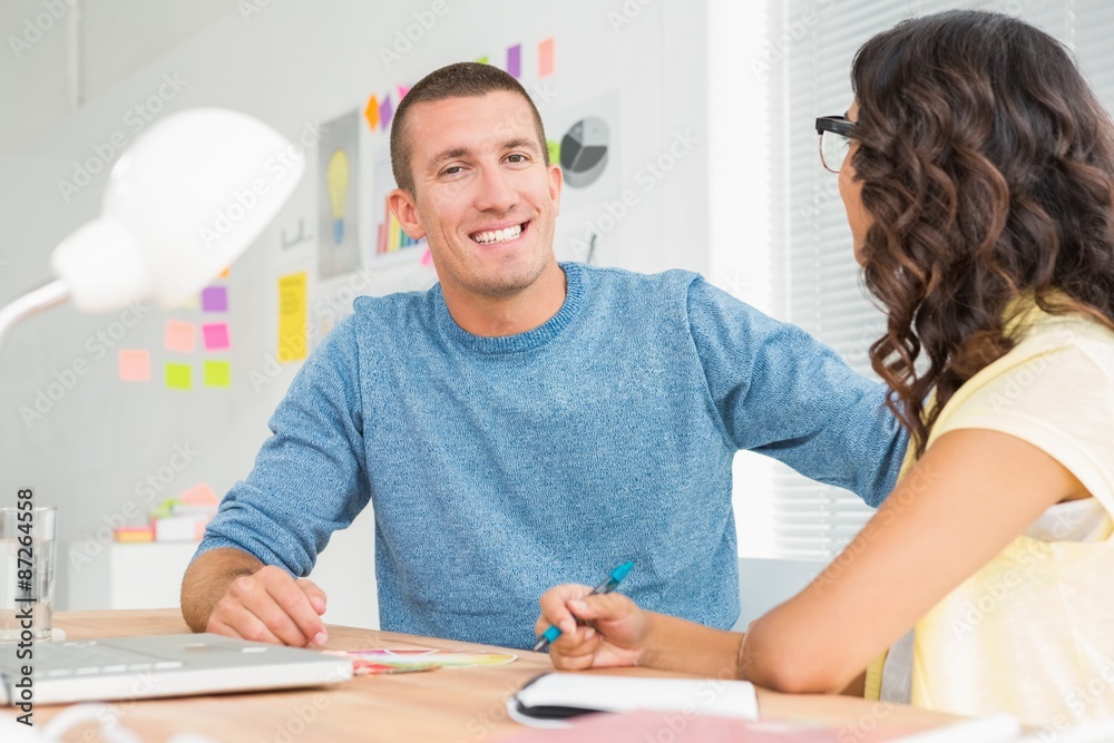 Smiling man speaking to his colleague and looking at camera Smiling man speaking to his colleague and looking at camera