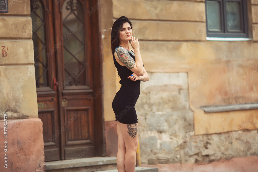 beautiful girl in a black dress stands near architectural struct