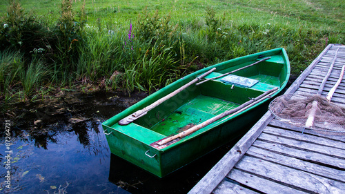 Fototapeta Naklejka Na Ścianę i Meble -  Zielona łódka nad brzegiem stawu na Warmii i Mazurach