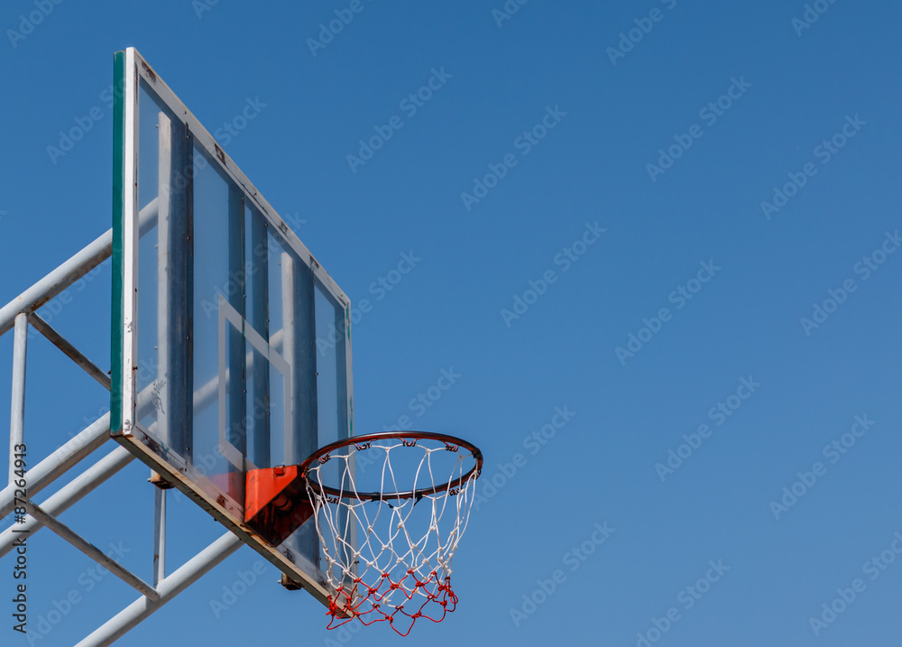 Basketball board and hoop with blue sky.