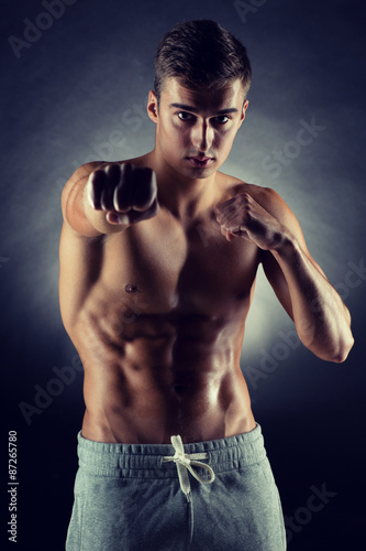 young man on fighting stand over black background