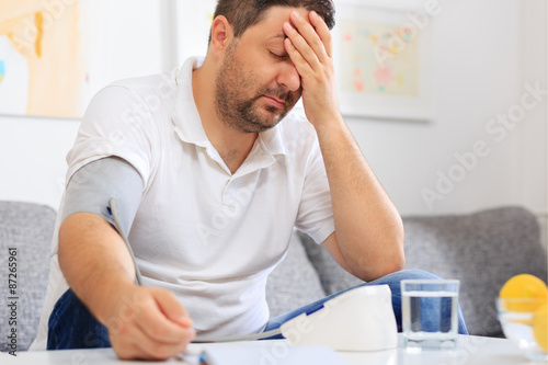 Man measuring his blood pressure feeling sick.