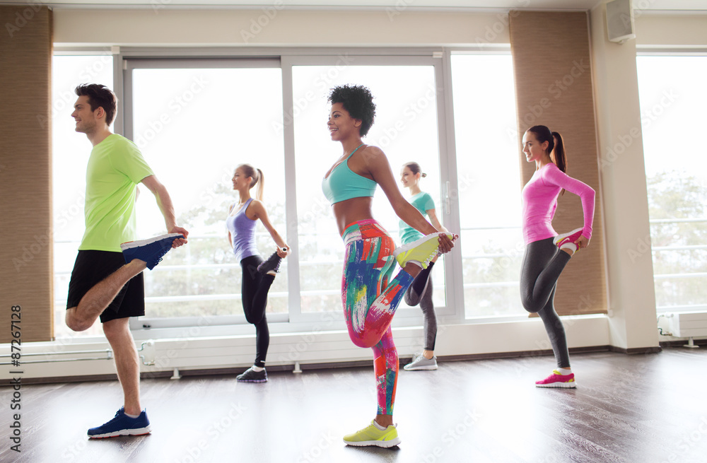 group of smiling people exercising in gym