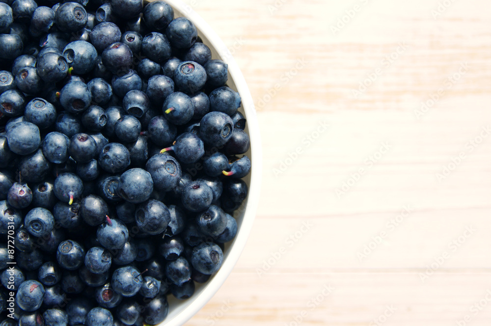 Fresh bilberry in a white ceramic bowl on a wooden surface Fresh bilberry in a white ceramic bowl on a wooden surface