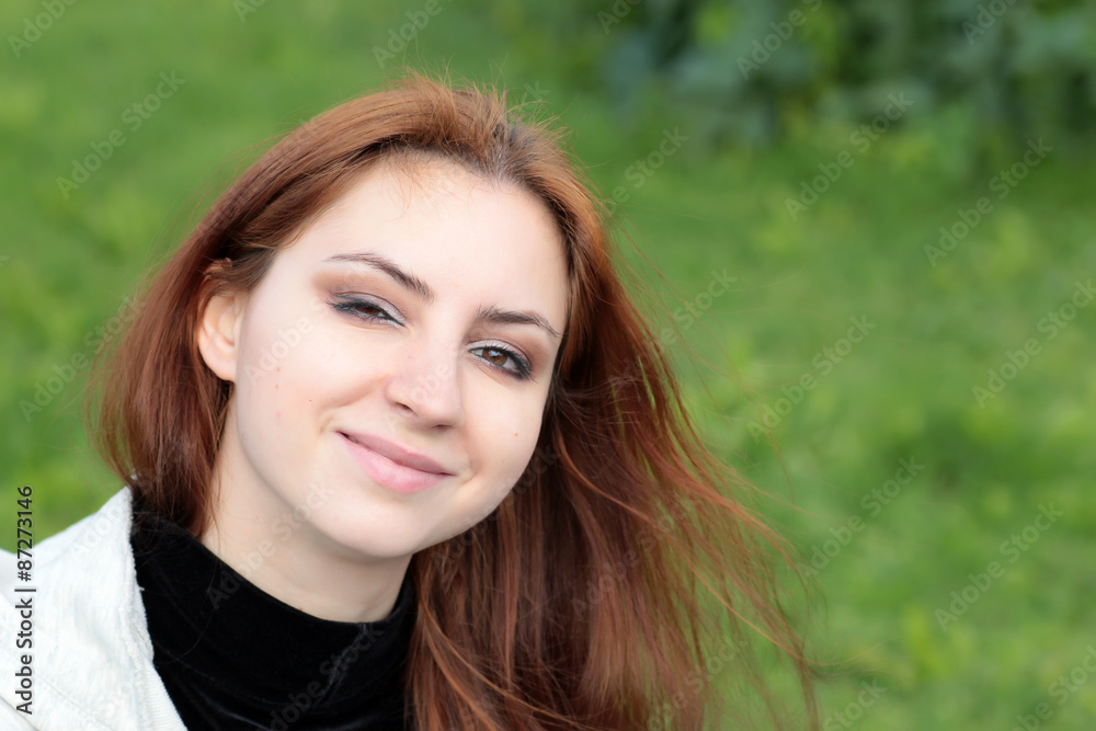 Portrait of red-haired girl in the park