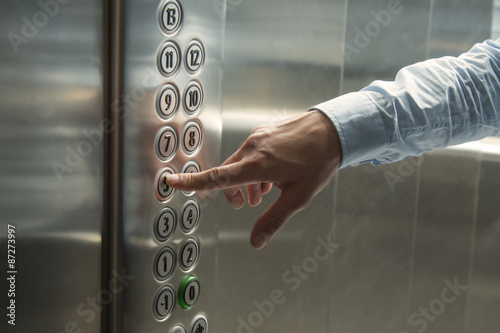 Finger pressing the button in the elevator photo