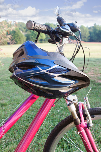 Helmet Hanging on Bicycle – A bicycle safety helmet hangs from the handlebars of a bike.