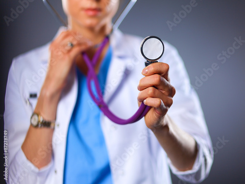 Female doctor with a stethoscope listening, isolated on grey