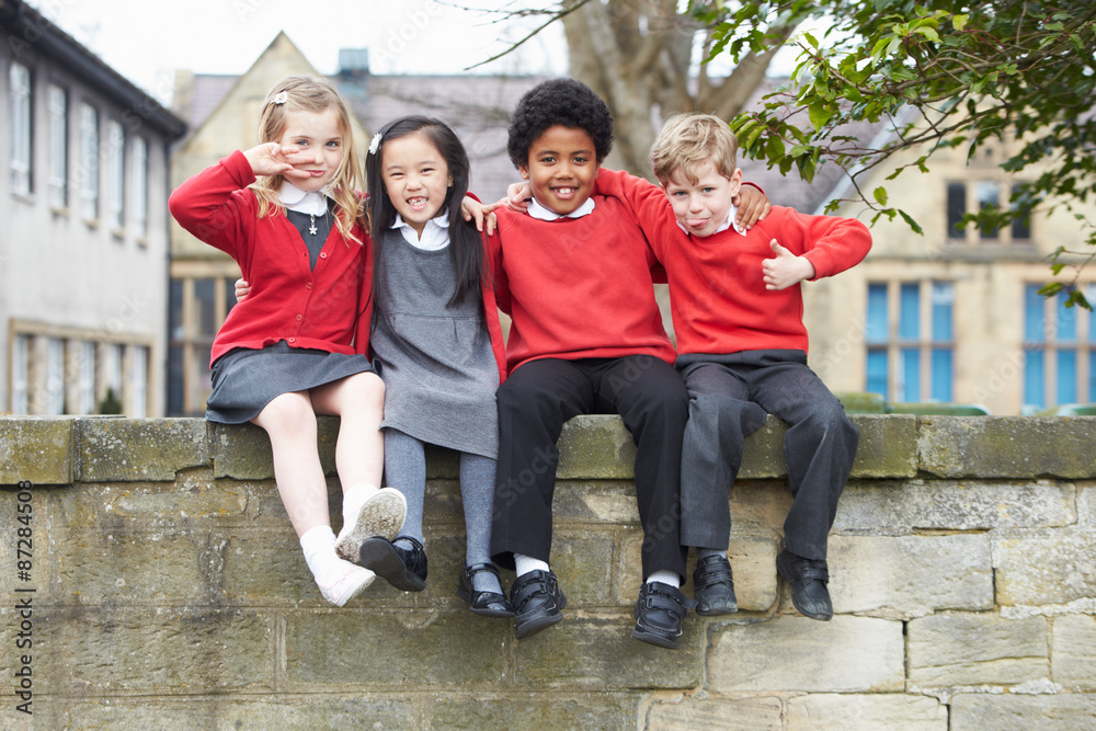 Portrait Of School Pupils Sitting On Wall Together