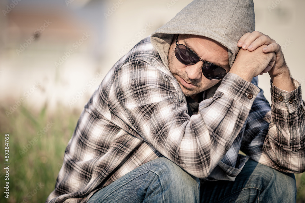 Portrait of a sad man in sunglasses sitting near the house Portrait of a sad man in sunglasses sitting near the house