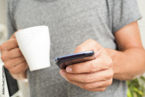 young man with a cup of coffee using a smartphone