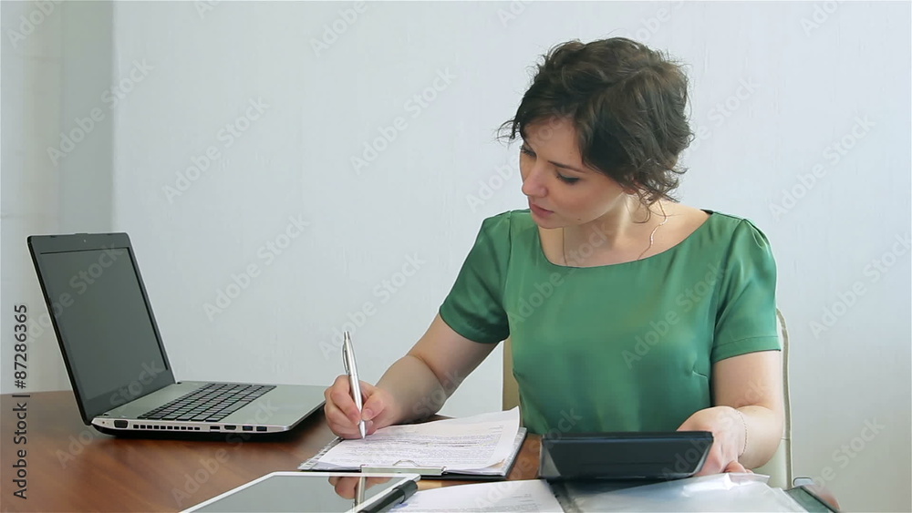 Woman counts on the calculator. Young woman considers using the calculator
Woman counts on the calculator. Young woman considers using the calculator