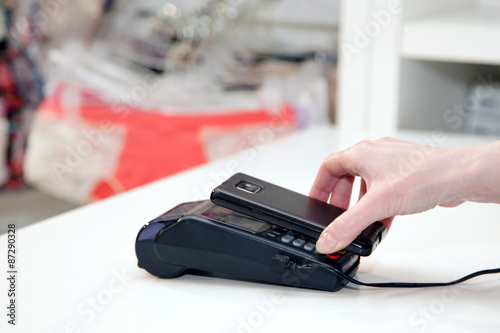 Hand closeup pays with NFC technology to a mobile phone