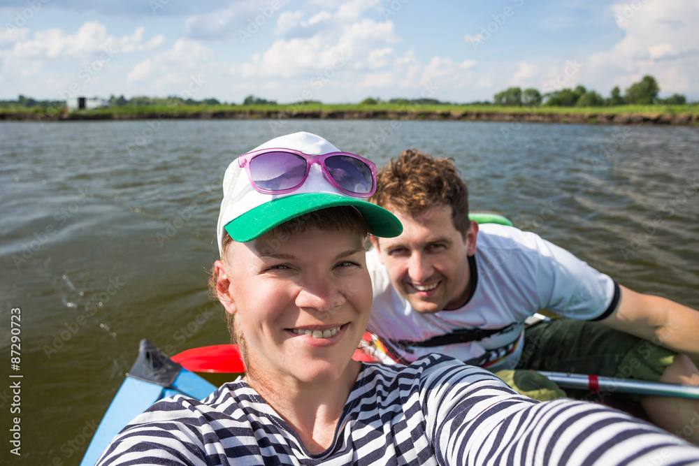 Fototapeta premium Young people make selfie during kayaking on a river in beautiful nature