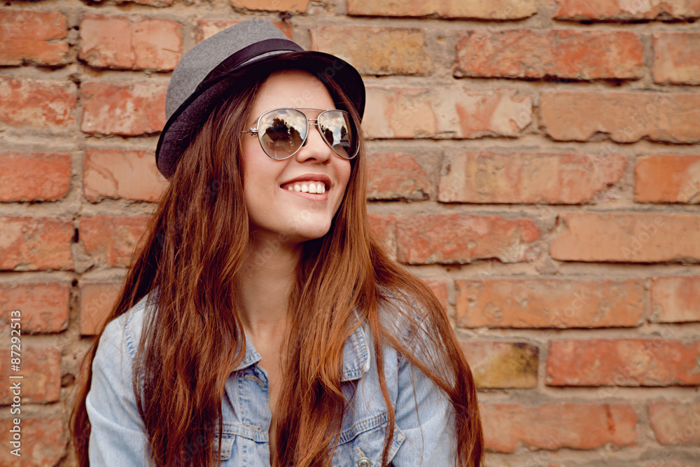 Obraz premium Happy beautiful woman stands near the old brick wall. 