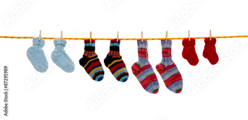 Selbst gestrickte Kinder Socken isoliert auf weiß hängend auf einer Wäscheleine mit Wäscheklammer
