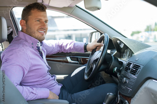 Attractive young businessman is sitting at steering wheel © Yakobchuk Olena