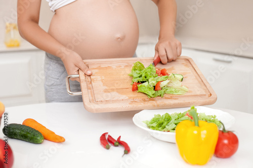 Young pregnant woman is cooking healthy food