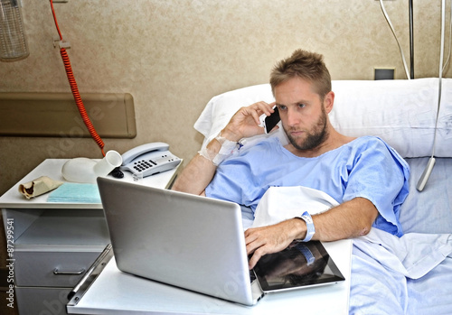 workaholic businessman in hospital room sick working with computer laptop photo