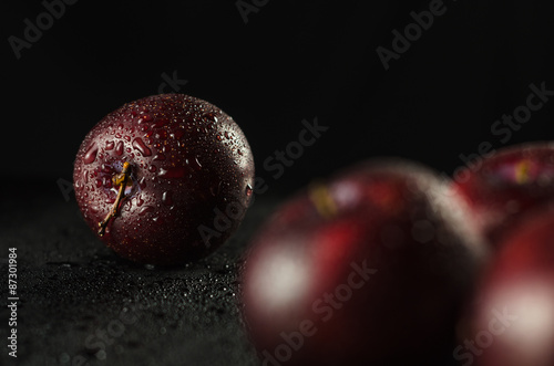 Tableau sur toile Low key shot of Plums on a black, smooth and wet surface