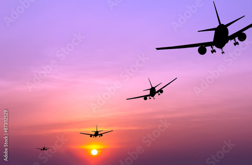 Fototapeta Naklejka Na Ścianę i Meble -  Silhouetted commercial airplane flying at sunset
