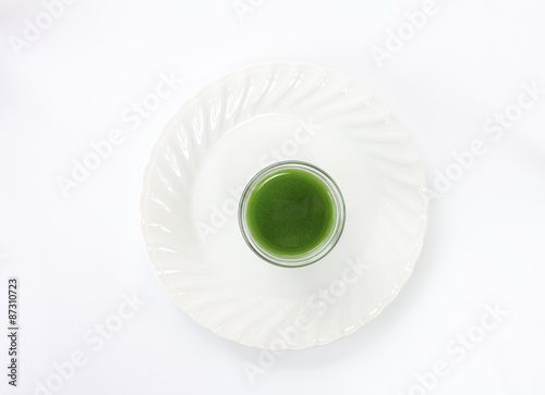 青汁をコップに入れて白い皿の上に乗せて上から見下ろす