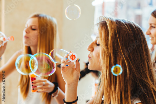 On a day of rest  at a party  a group of three young women friends enjoy doing soap bubbles in a city under the arcades