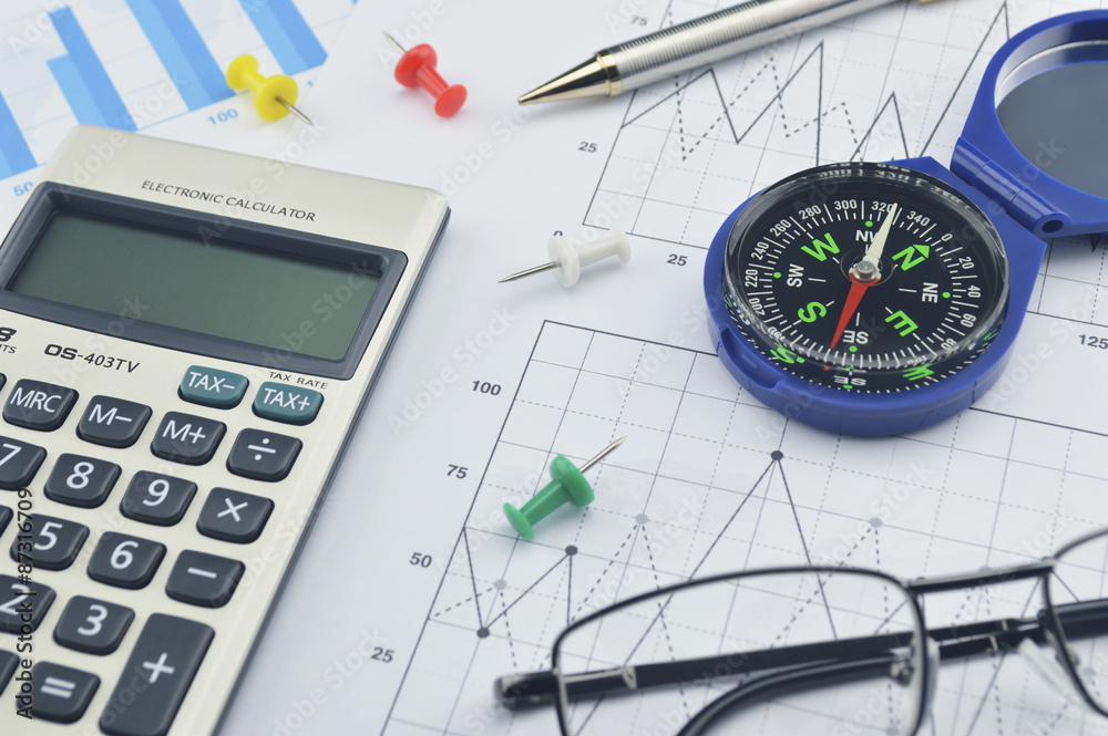 Blue compass, calculator, pen and glasses on graph paper, succes Blue compass, calculator, pen and glasses on graph paper, succes