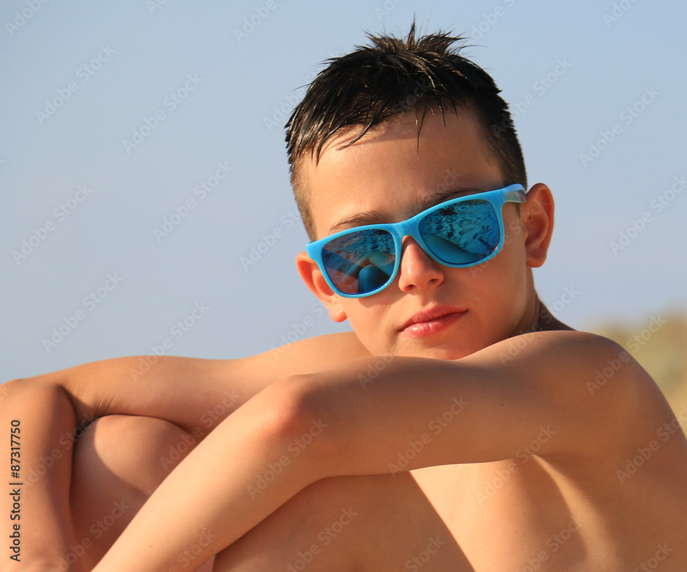 Portrait of young boy wearing sunglasses and posing by sea Portrait of young boy wearing sunglasses and posing by sea