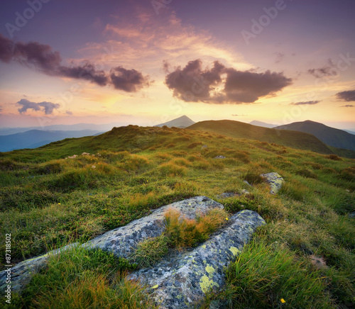 Mountain field with stones during bright sunset. Natural summer landscape
