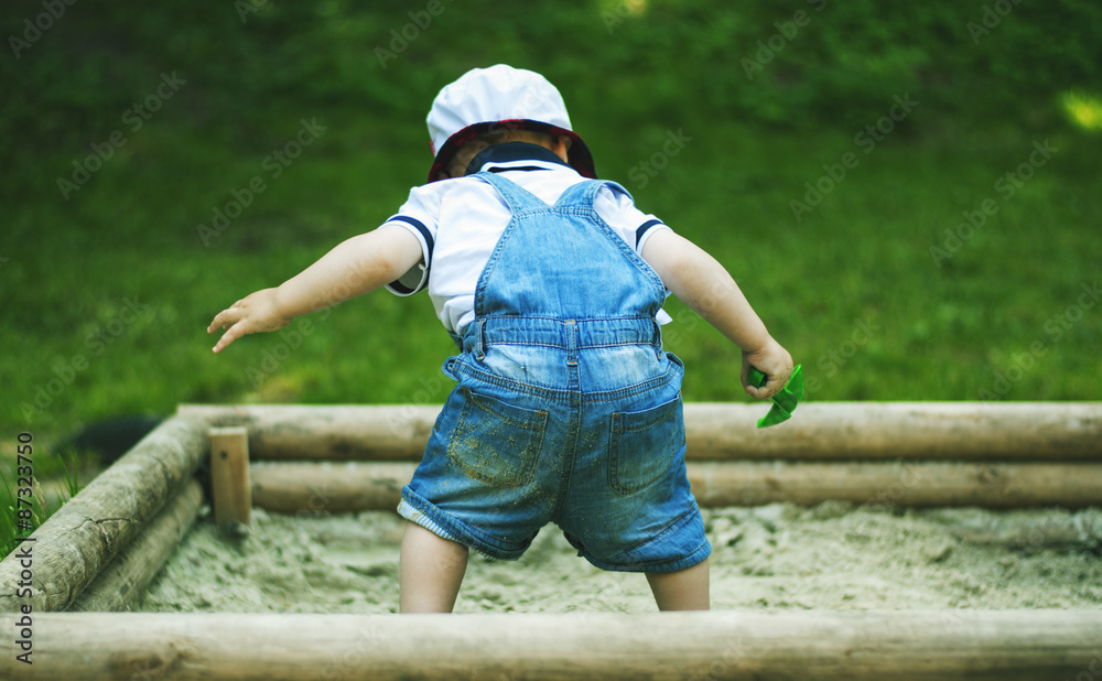 small boy playing in sandbox