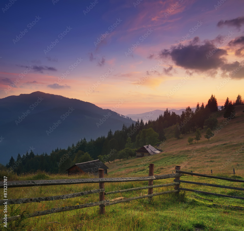 Fence in mountain valley. Agricultural landscape during sunrise.