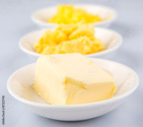 A block of butter, margarine and ghee in white bowls 