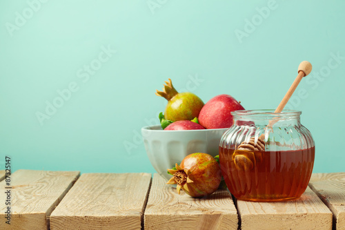 Honey jar and pomegranate on wooden table with copy space