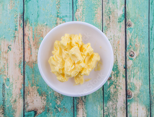 A bowl of margarine in white bowl over wooden background