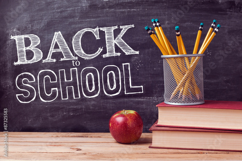 Back to school lettering with books, pencils and apple over chalkboard background