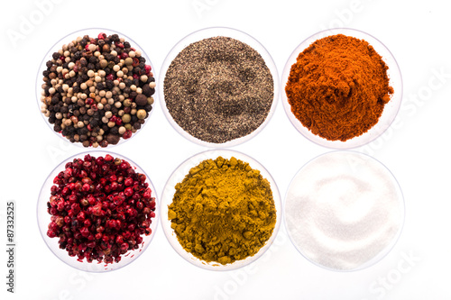 Fototapeta Naklejka Na Ścianę i Meble -  Pfeffer, Salz, Curry und Paprika in Schalen arrangiert vor weißem Hintergrund