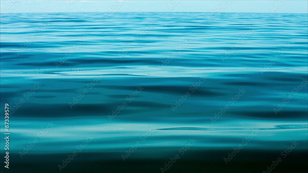 Blue calm sea water background with gently moving waves creating a relaxing atmosphere Blue calm sea water background with gently moving waves creating a relaxing atmosphere