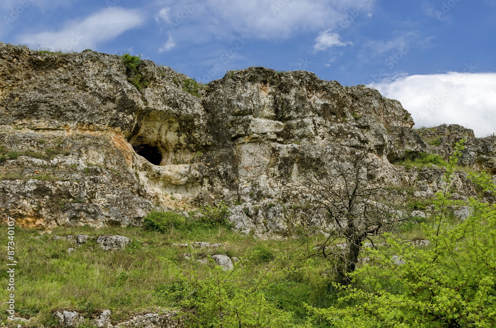 General view toward sedimentary rock with cave in the field, Ludogorie, Bulgaria 